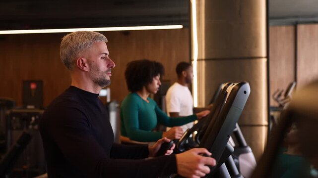 Diverse group of people training on elliptical machines at the gym
