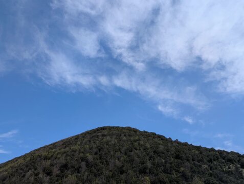   
Montagna ricoperta da fitta vegetazione sotto un cielo parzialmente nuvoloso, una scena naturale luminosa e tranquilla