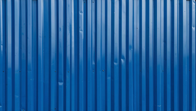 A weathered blue corrugated metal fence in a state of disrepair with rust spots and cuts.