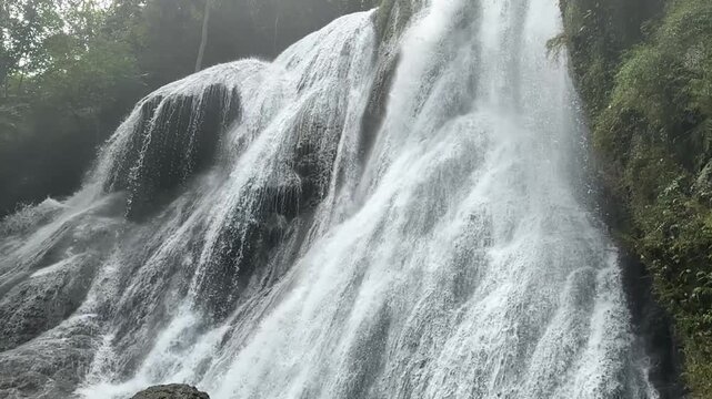 Majestic waterfall with powerful cascades through lush tropical forest. Ideal for relaxation, meditation, travel, and environmental content, promoting natural beauty, eco-tourism, and tranquility.