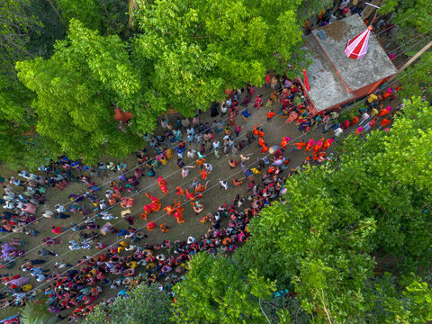 Munshiganj, Bangladesh - 13 April 2026: Aerial view of a vibrant gathering near a small temple, its red and white flag a stark contrast to the surrounding lush greenery.