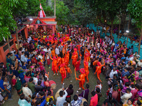 Munshiganj, Bangladesh - 13 April 2026: Aerial view of vibrant orange-clad performers captivating a dense, colorful crowd on the sacred ground of a temple.