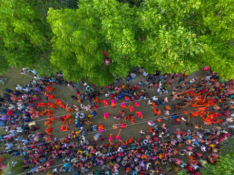 Munshiganj, Bangladesh - 13 April 2026: Aerial view of a vibrant, colorful crowd celebrating under a lush green tree canopy, a vivid scene of human joy.