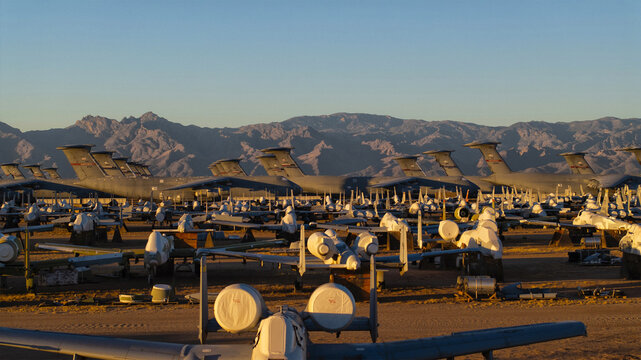 Aerial view of retired aircraft silently rest in the desert sun, their metallic bodies reflecting the soft glow of the setting sun, Tucson, Arizona, United States.
