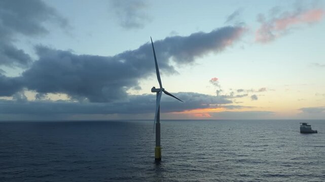 Beautiful view of an offshore wind turbine producing clean, renewable energy. Majestic sunrise over the calm sea on the coast of Gran Canaria