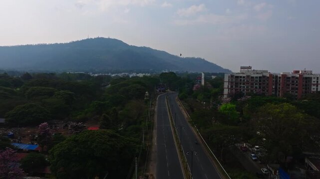 Chamundi hills with road, street lights, trees and Brigade Mountain View apartments at Mysuru, karnataka, india. day time, zib shot, drone shot, 4k.