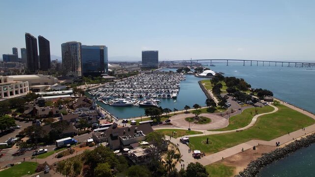 Drone flying toward the marina in downtown San Diego at 12 noon capturing boats, water, and surrounding city structures.