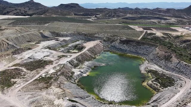 An orbiting drone shot of a massive open-pit mine and water depuration plant, showing the scale of excavation against the arid Spanish landscape.