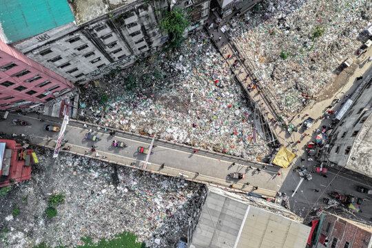Keraniganj, Bangladesh - 11 April 2026: Aerial view of a busy bridge bisecting a sprawling landfill, a grim landscape of waste contrasting with human passage.
