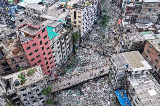 Keraniganj, Bangladesh - 11 April 2026: Aerial view of a river choked with plastic waste flowing through the heart of the city, contrasting sharply with the adjacent buildings.