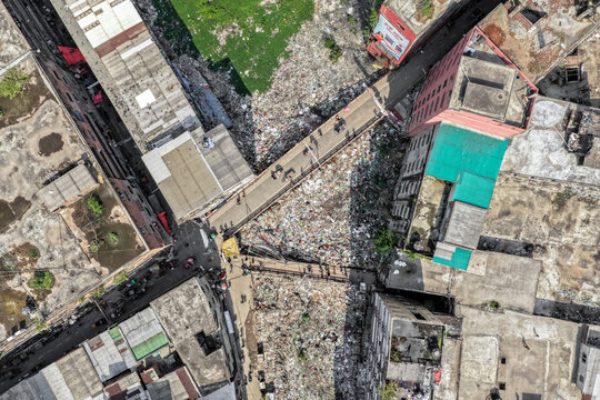 Keraniganj, Bangladesh - 11 April 2026: Aerial view of a bridge crossing a landscape of discarded refuse, contrasting sharply with the adjacent buildings.