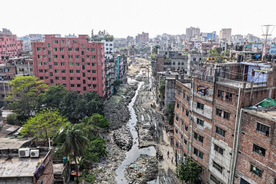 Keraniganj, Bangladesh - 11 April 2026: Aerial view of a densely packed urban landscape where vibrant buildings flank a choked, debris-laden river.