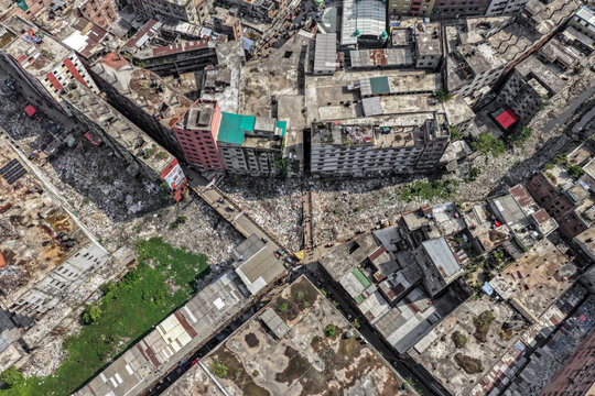 Keraniganj, Bangladesh - 11 April 2026: Aerial view of densely packed urban sprawl, with weathered concrete structures, contrasting bright white and dark refuse, and a sliver of vibrant green.