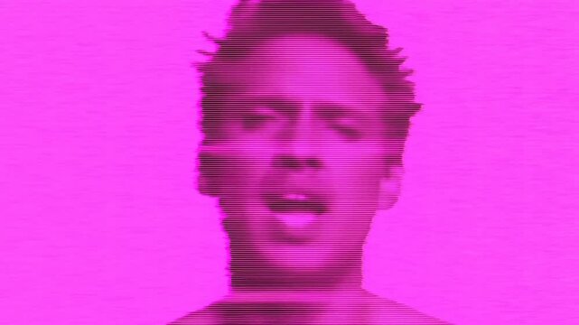 Static shot of male portrait turning head and moving mouth with horizontal scanline glitch on solid pink studio background