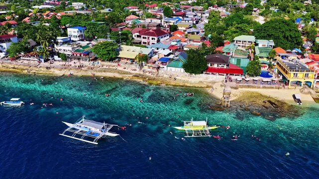 Moalboal beach resort area with coral reef and outrigger boats aerial