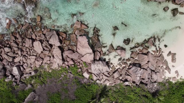 Bird eye drone view of granites stones near shoreline, clear turquoise water, people snorkelling, anse cocos, La Digue, Seychelles 006