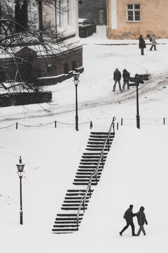 Tallinn, Estonia - 03 January 2025: View of snow-draped historic architecture and steep stairs, with dark figures traversing the pristine white landscape.