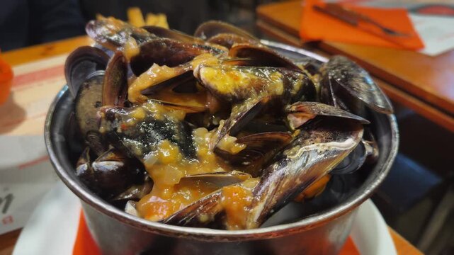 Steaming mussels served with a spicy onion sauce in a restaurant specializes in mussel dishes, tender, rich, and irresistibly tasty. High quality 4k footage