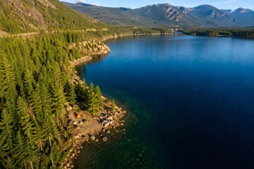 Fototapeta premium Aerial view of mountain lake campsite with forest and tent