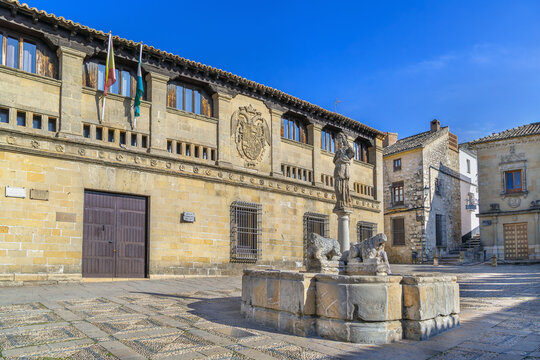 Fountain of the Lions and Antiguas Carnicerias in Baeza, Spain. Renaissance architecture with coat of arms under blue sky.