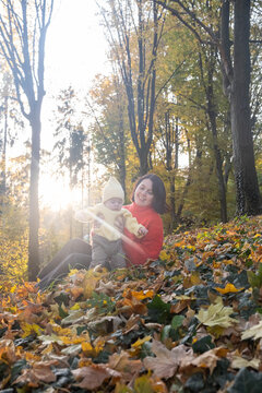 Mother and Baby Enjoying Autumn in Sunlit Forest Copy Space