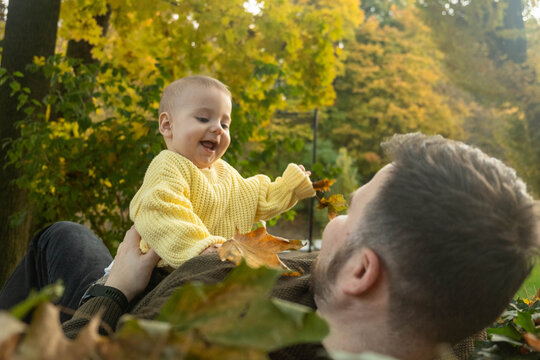 Father and Baby Enjoying Autumn Leaves.