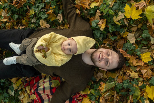 Father and Baby Enjoying Autumn Leaves Overhead