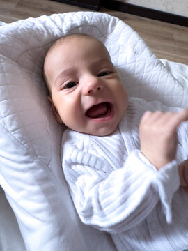 Smiling newborn baby on soft white pillow at home portrait
