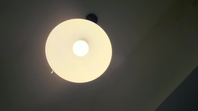 Low angle view looking up at a glowing round ceiling pendant lamp modern interior light