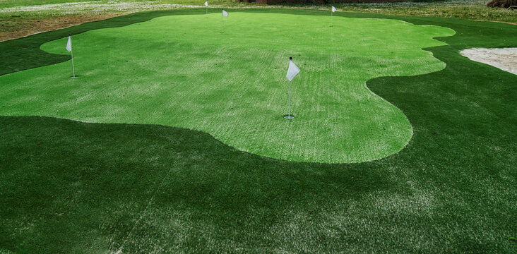 Artificial grass mini golf course with several flags and holes ready for playing
