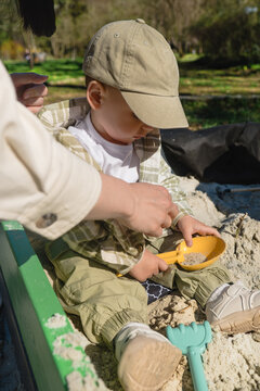 Toddler playing in sandbox with parent help close up