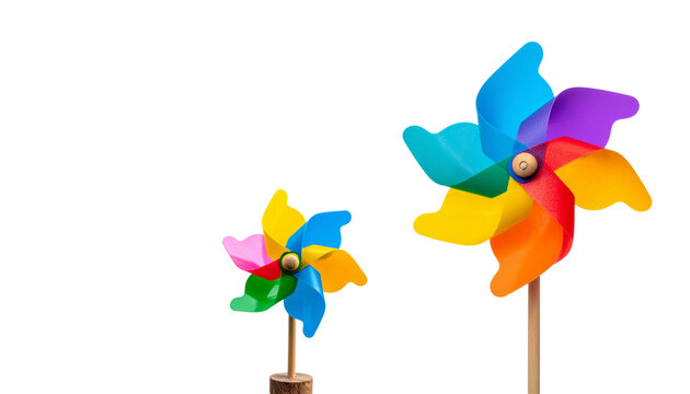 A colorful, detachable paper windmill toy with spinning rainbow-colored plastic blades sits on a white background.