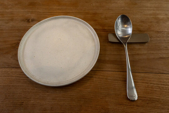 Empty Ceramic Plate and Spoon on Rustic Wooden Restaurant Table