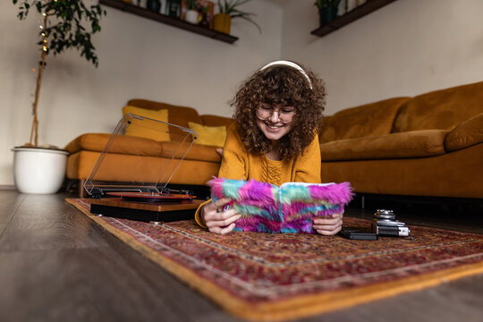 Smiling person reading a notebook and listening to music indoors