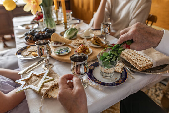 Family dipping parsley during indoor Passover seder meal
