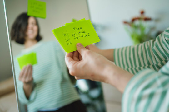 Hand holding a motivational affirmation note in front of a mirror
