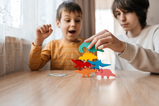 Brother stacking wooden dinosaur toy indoors