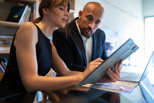 Businesswoman and colleague review document on clipboard in office