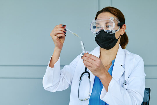 Scientist with mask using pipette for research in laboratory