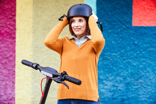 Smiling woman wearing helmet in front of multi colored wall