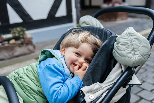 Happy child laughing in a stroller during an outdoor walk