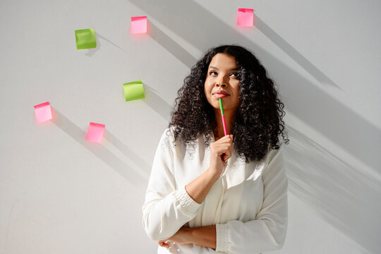 Creative businesswoman brainstorming with sticky note on white wall