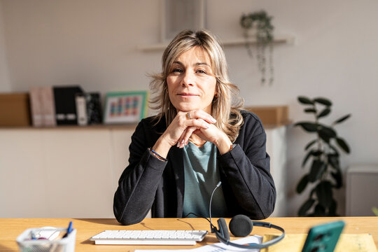 Mature woman in a home office setting looking at the camera with a calm expression