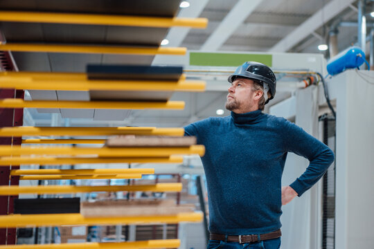 Thoughtful businessman wearing hardhat standing in industry