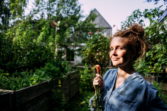 Woman holding carrot at back yard