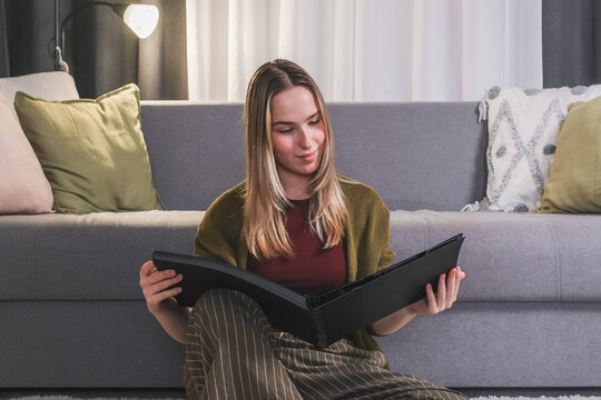 Young smiling and looking at a photo album in a cozy living room