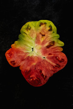 Top view of fresh sliced organic heirloom tomato on black background