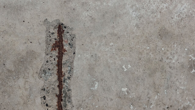 Exposed rusted rebar in spalled concrete surface with aggregate detail