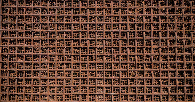 Rusty metal wire mesh texture. Close-up of the rusty texture of an industrial metal fence.