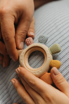 Hands holding baby teething toy on pregnant belly, ожидание малыша concept, close-up detail